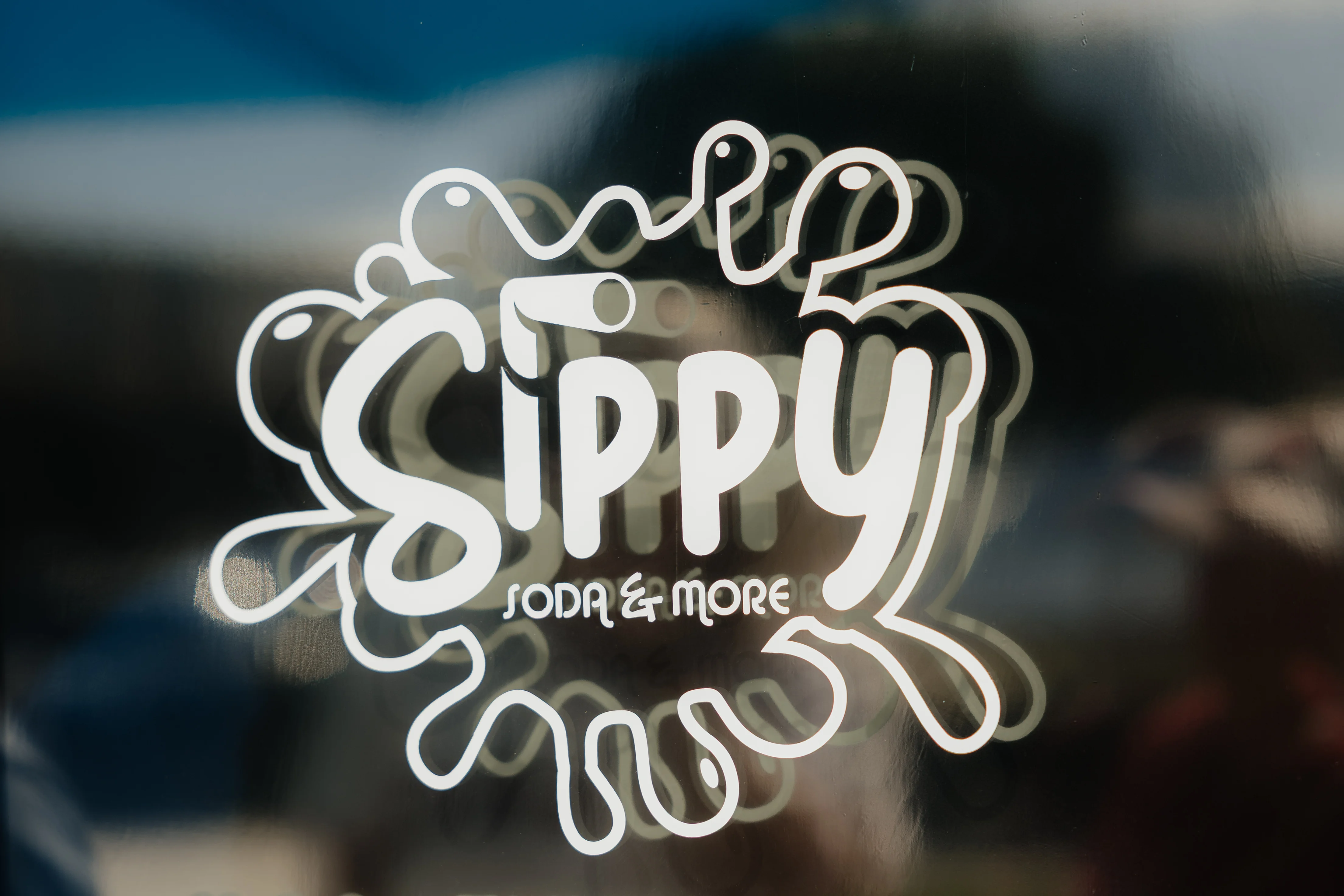 Sippy Soda & More logo with blue splash design