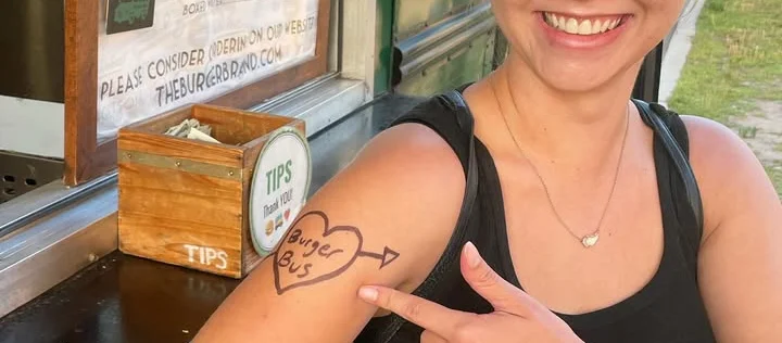 Smiling woman showing tattoo at food truck with menu