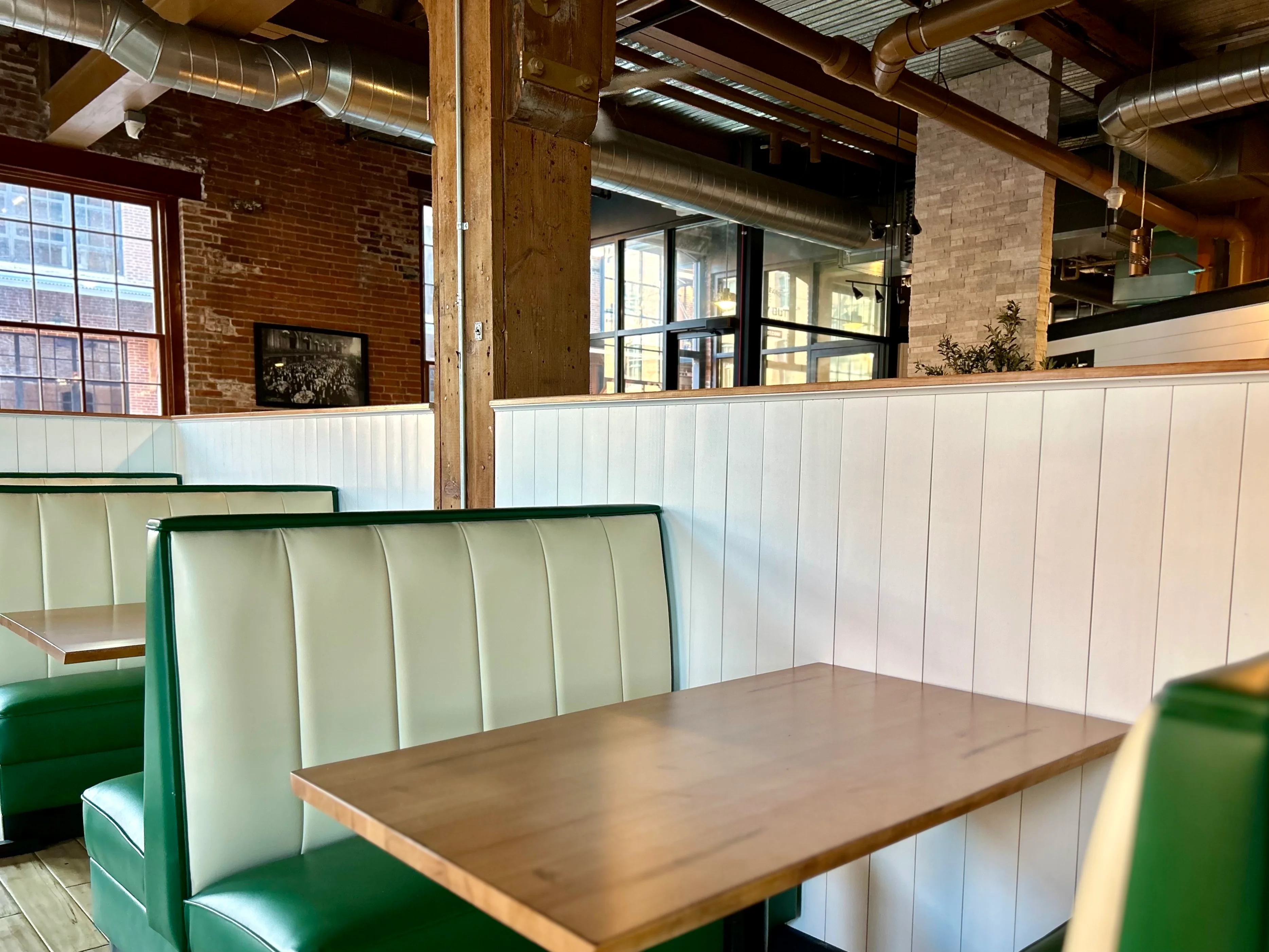 Cozy restaurant interior with green booths and exposed brick walls