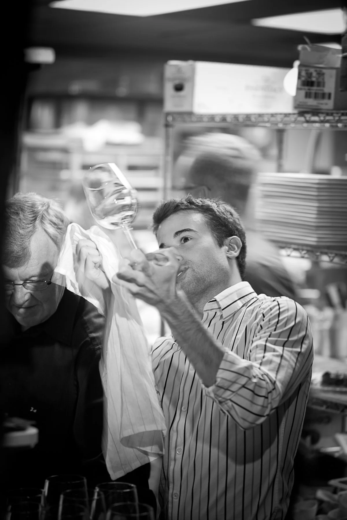 Staff polishing wine glasses in a bustling restaurant kitchen