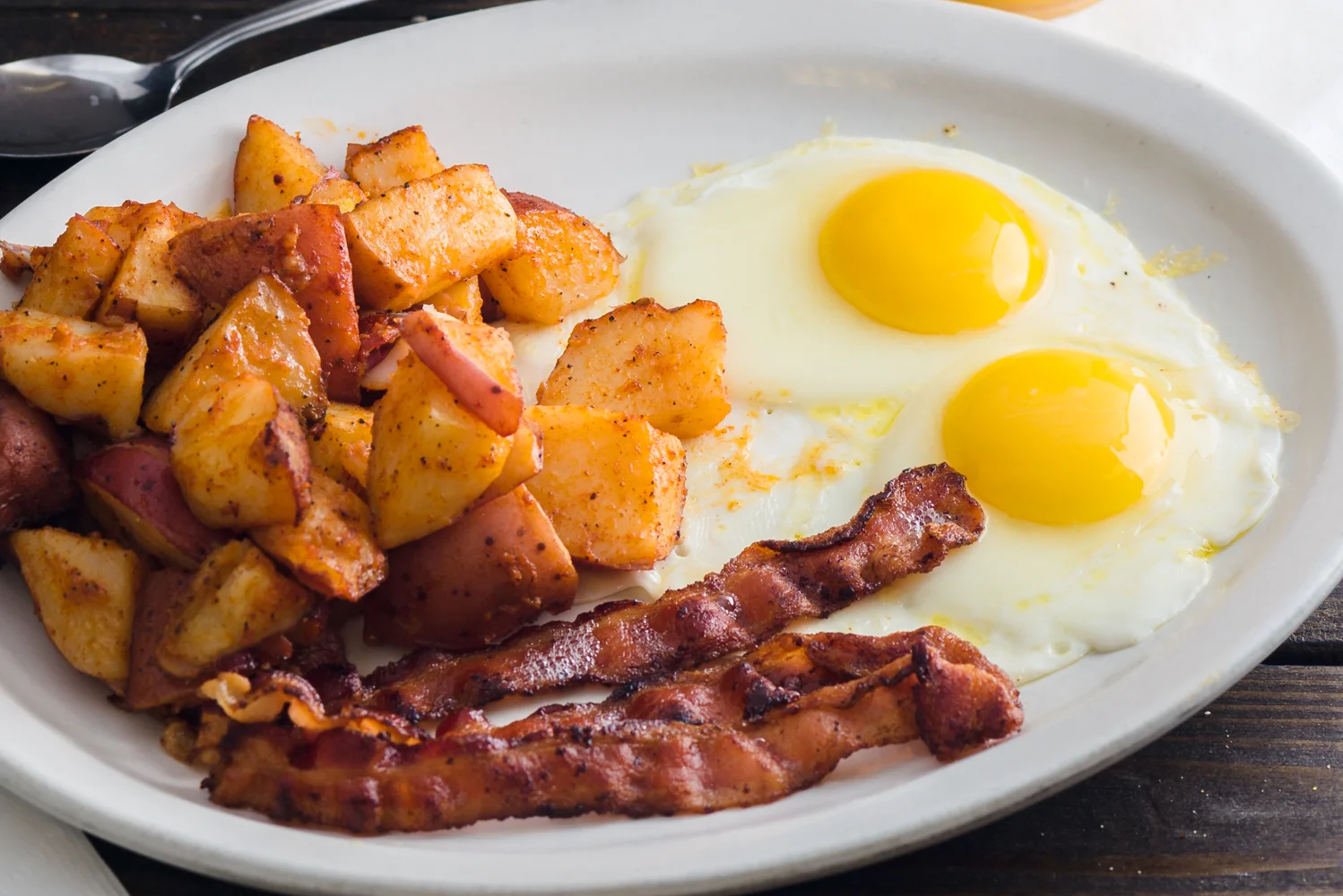Classic American breakfast with eggs, bacon, and seasoned potatoes