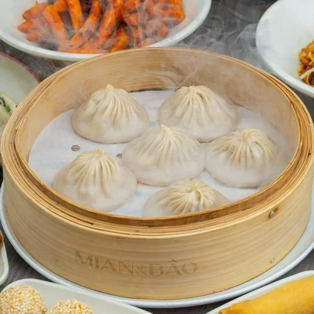 Delicious bao buns filled with savory ingredients on a wooden plate.