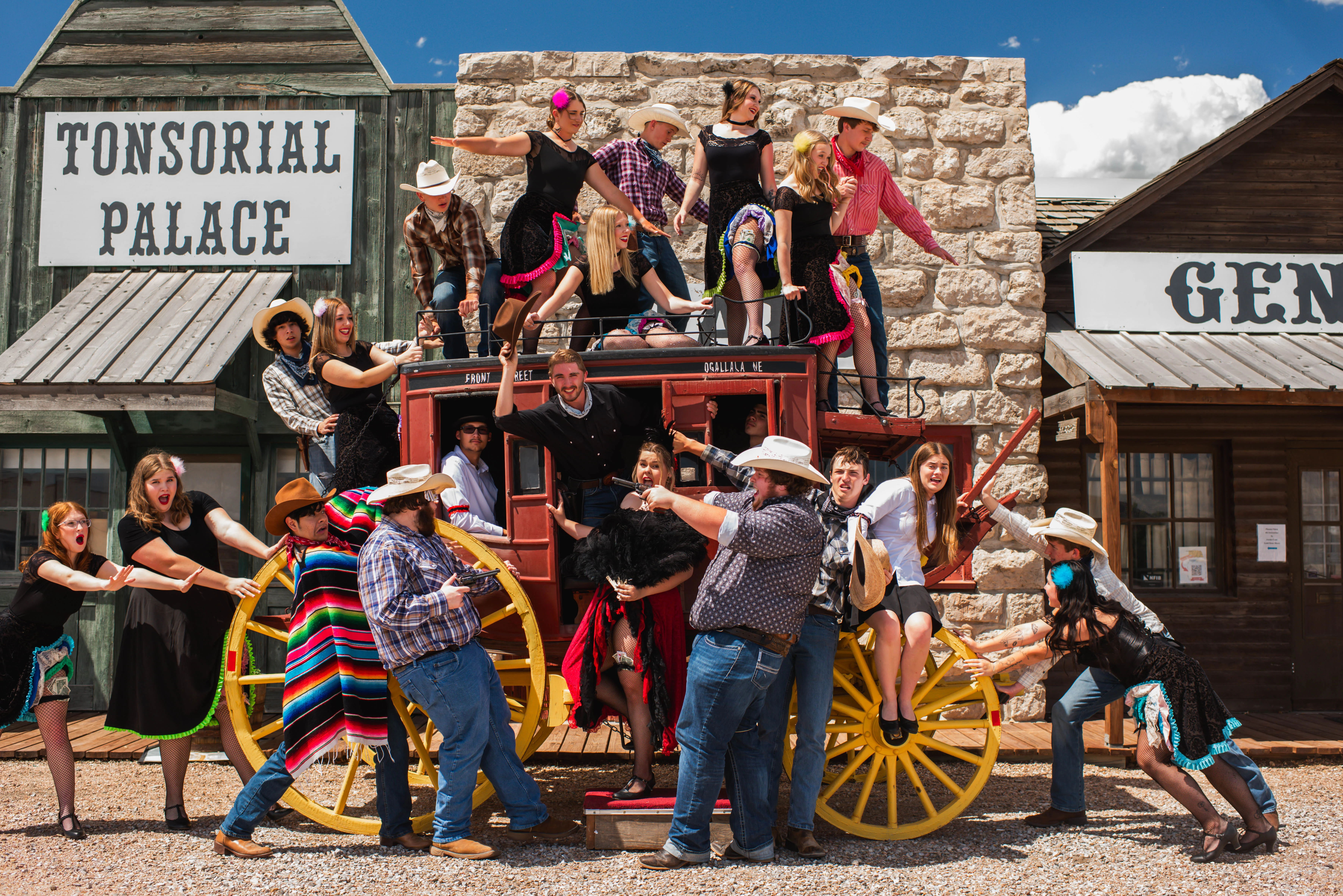 Group of people in cowboy attire posing by a vintage stagecoach