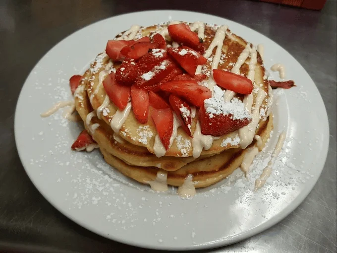 Stack of fluffy pancakes topped with syrup and butter