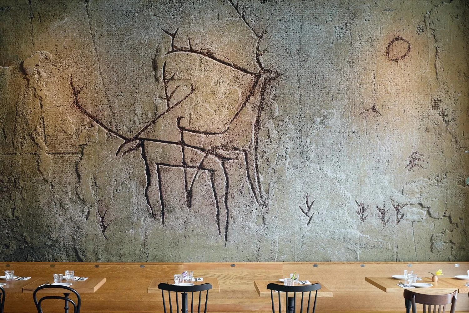 Restaurant interior featuring ancient cave art mural