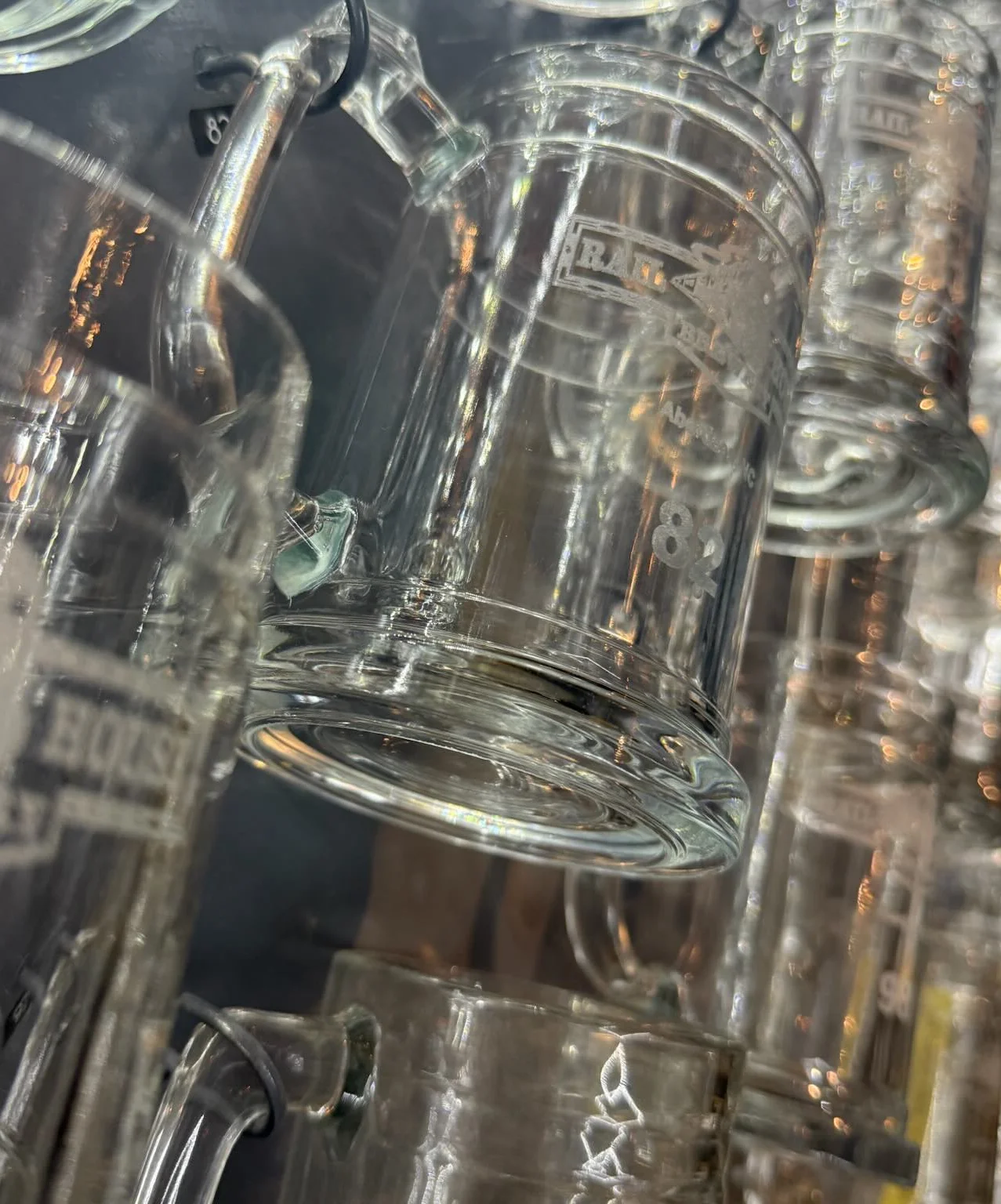 Collection of glass beer mugs hanging in a bar