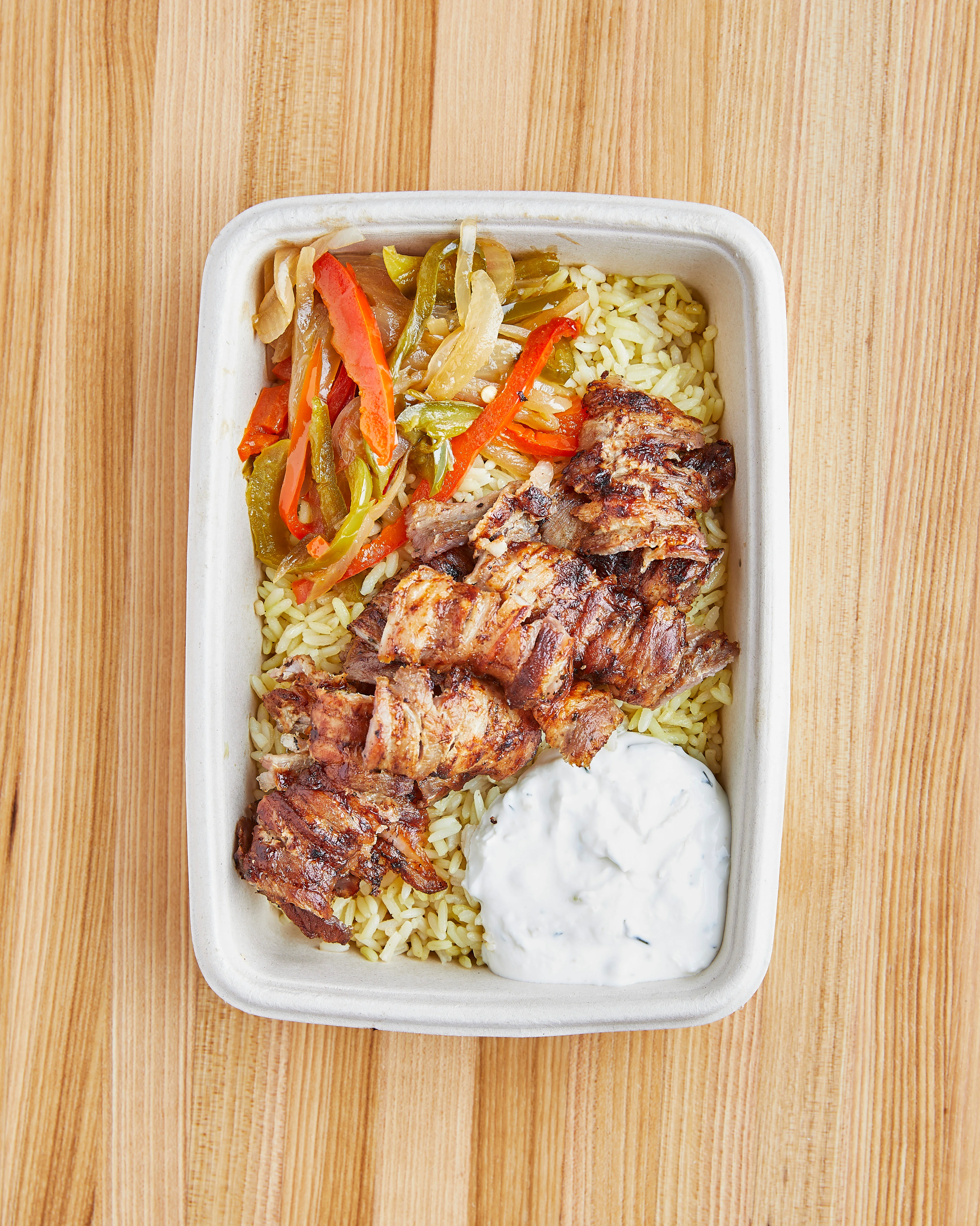 Grilled chicken shawarma over rice with vegetables and yogurt sauce