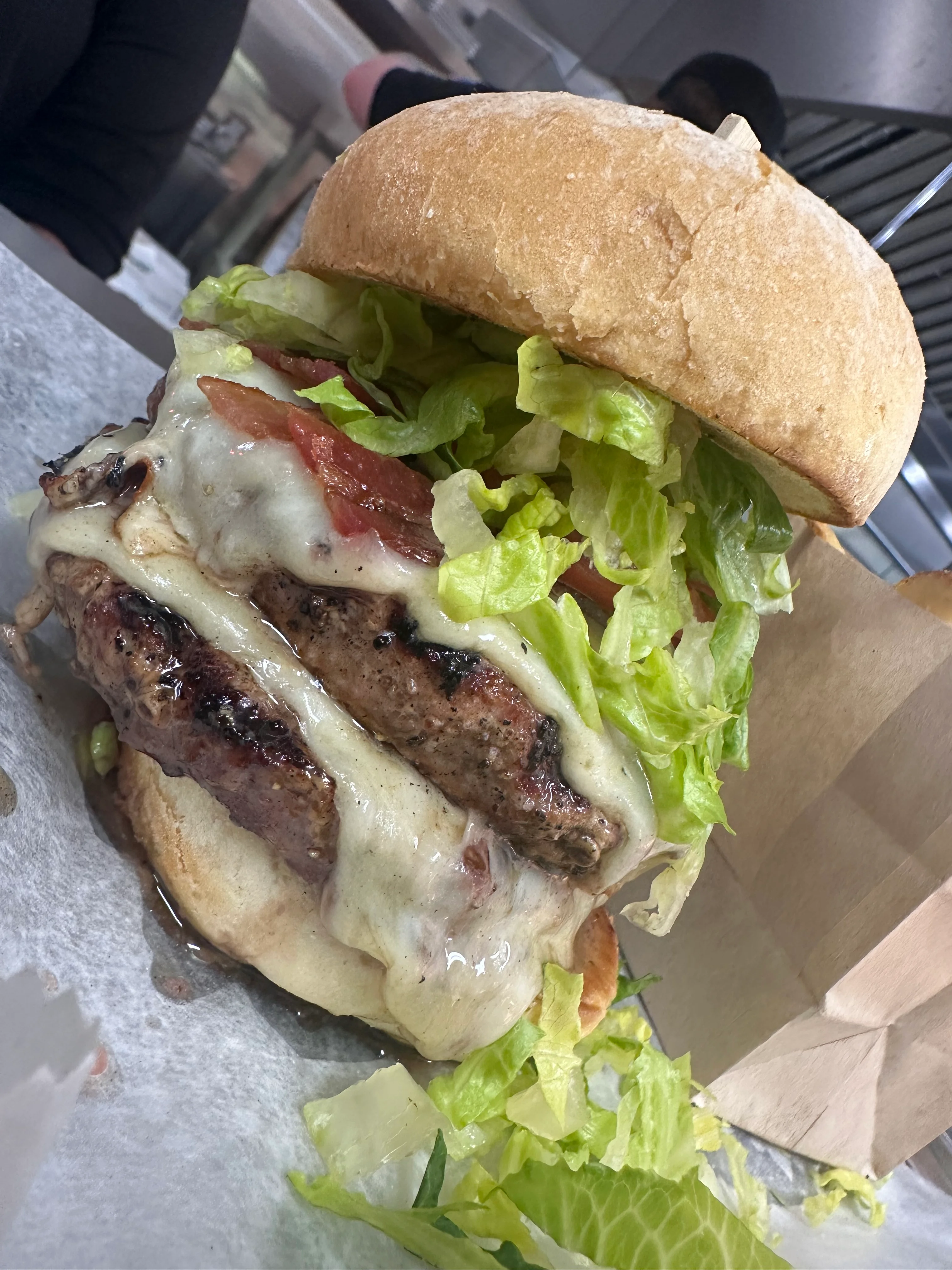 A towering burger with lettuce, tomato, and melted cheese on a bun.