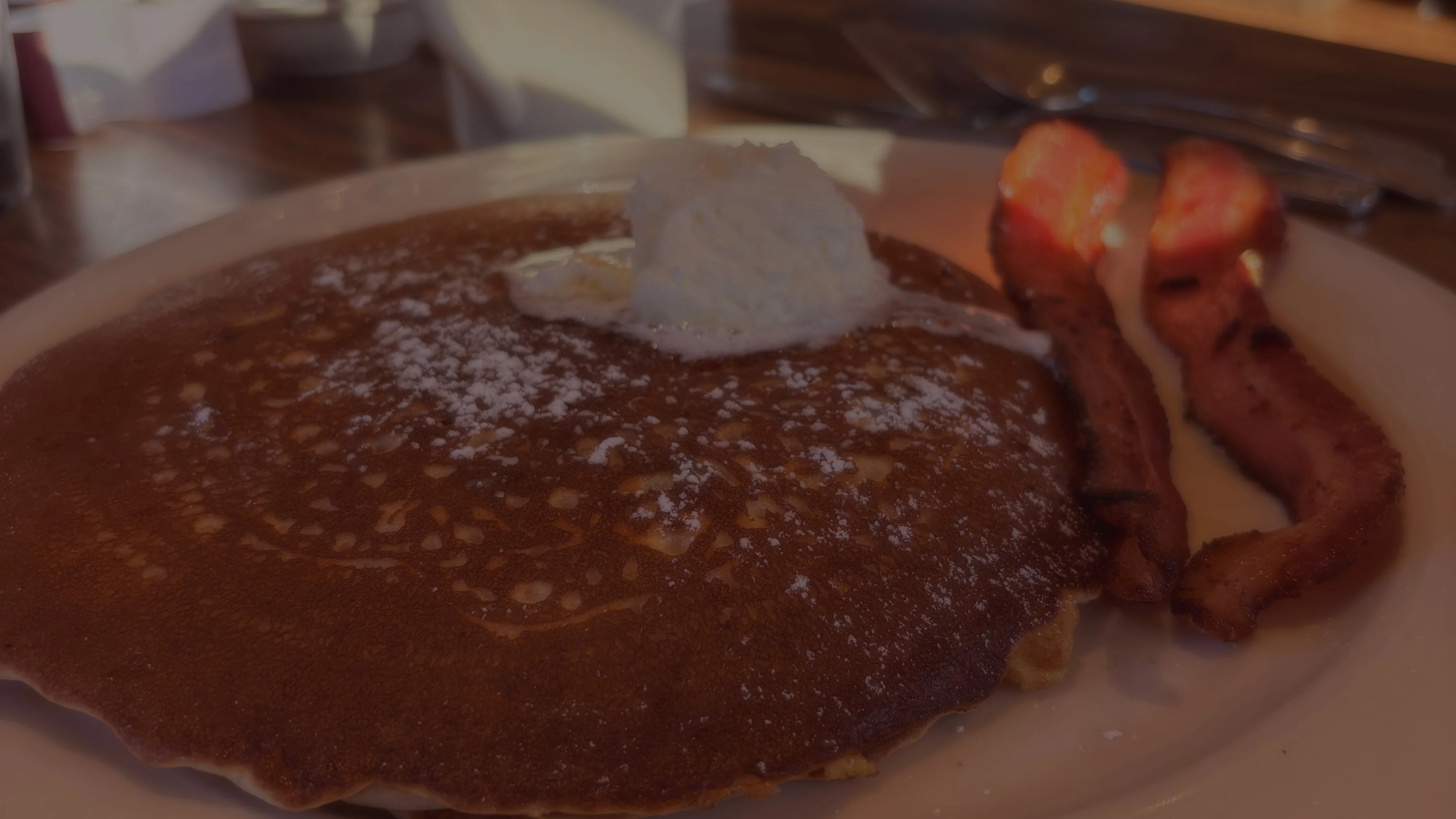 Fluffy buttermilk pancakes with whipped cream and crispy bacon