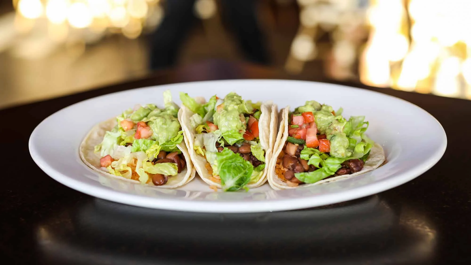 Three delicious vegetarian tacos with guacamole and fresh toppings