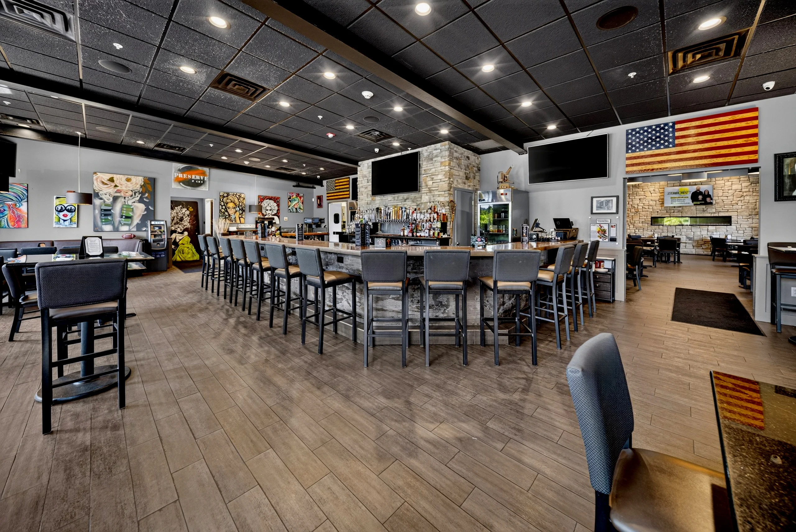 A photo of the inside of the restaurant showing the many seats of the bar and some hightops