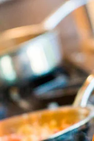 Chef stirring pasta in a busy kitchen