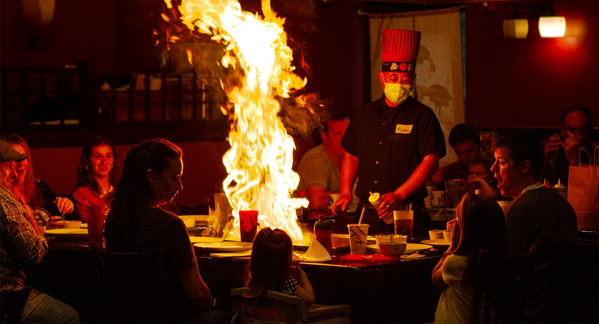Guests seated around a hibachi table watching the chef's fire show at Mahzu East Windsor