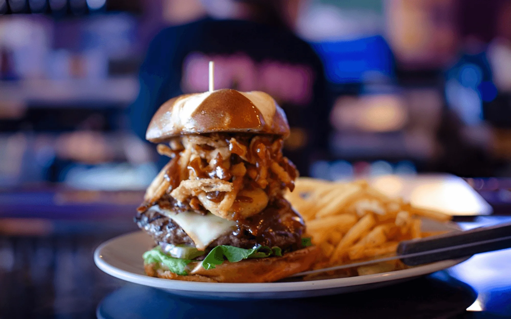 A fully stacked burger with loads of toppings and a side of fries