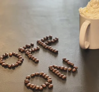 Coffee beans arranged to spell 'OFF' next to a whipped cream topped drink