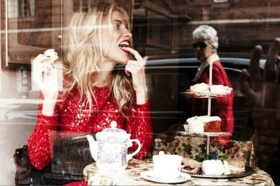 Woman enjoying afternoon tea with pastries in a cozy café setting