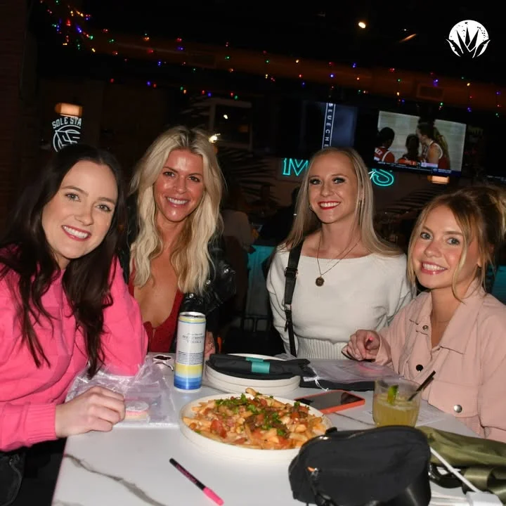 Group of friends enjoying a meal at a lively restaurant with festive decor.