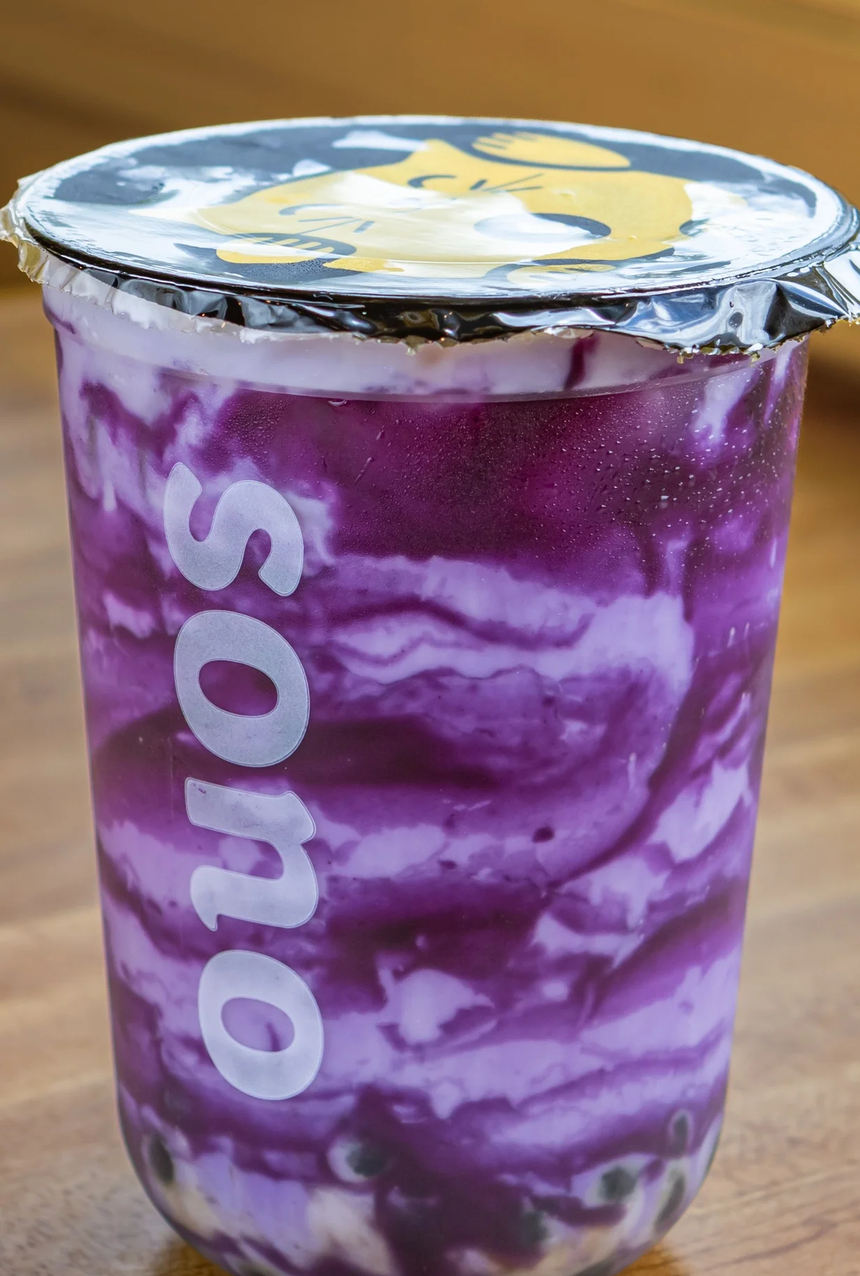 Purple ube drink with creamy swirls in a clear cup