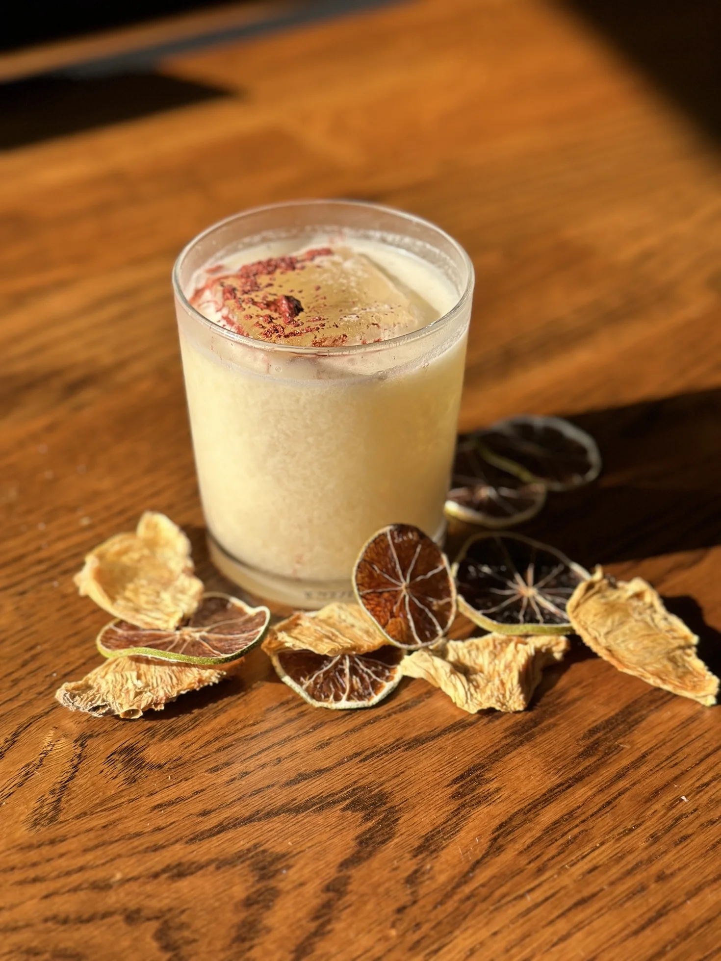 Craft cocktail with dried citrus garnishes on a wooden table