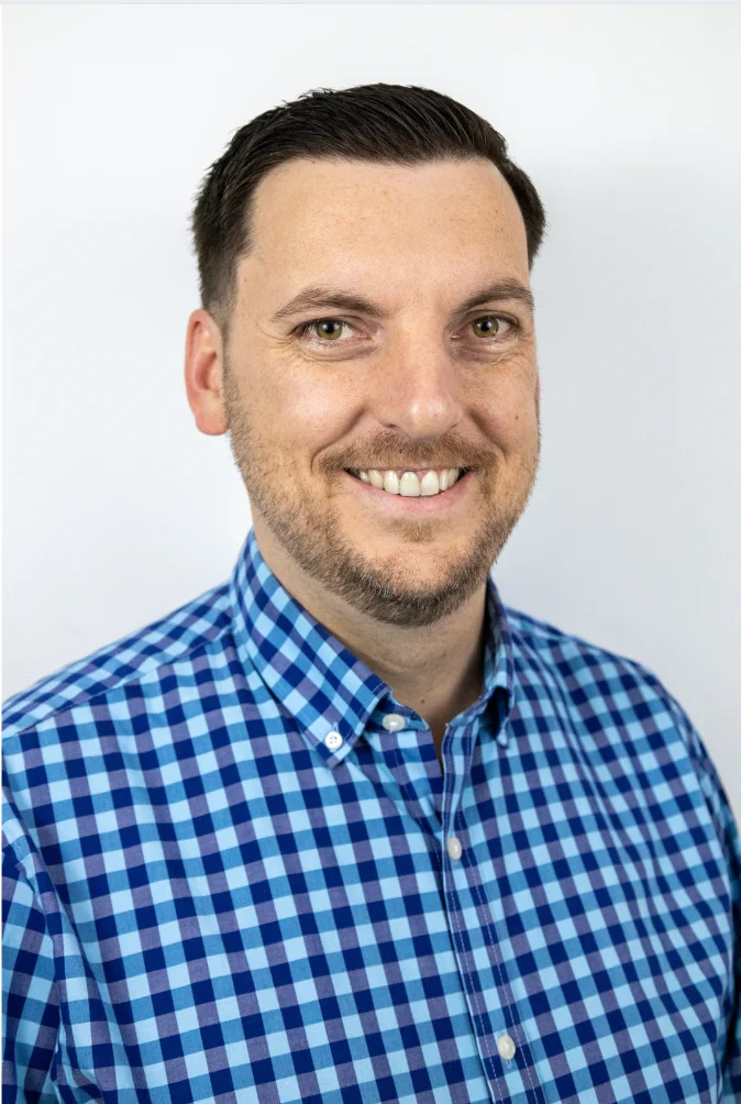 Professional headshot of a smiling man in a blue checkered shirt