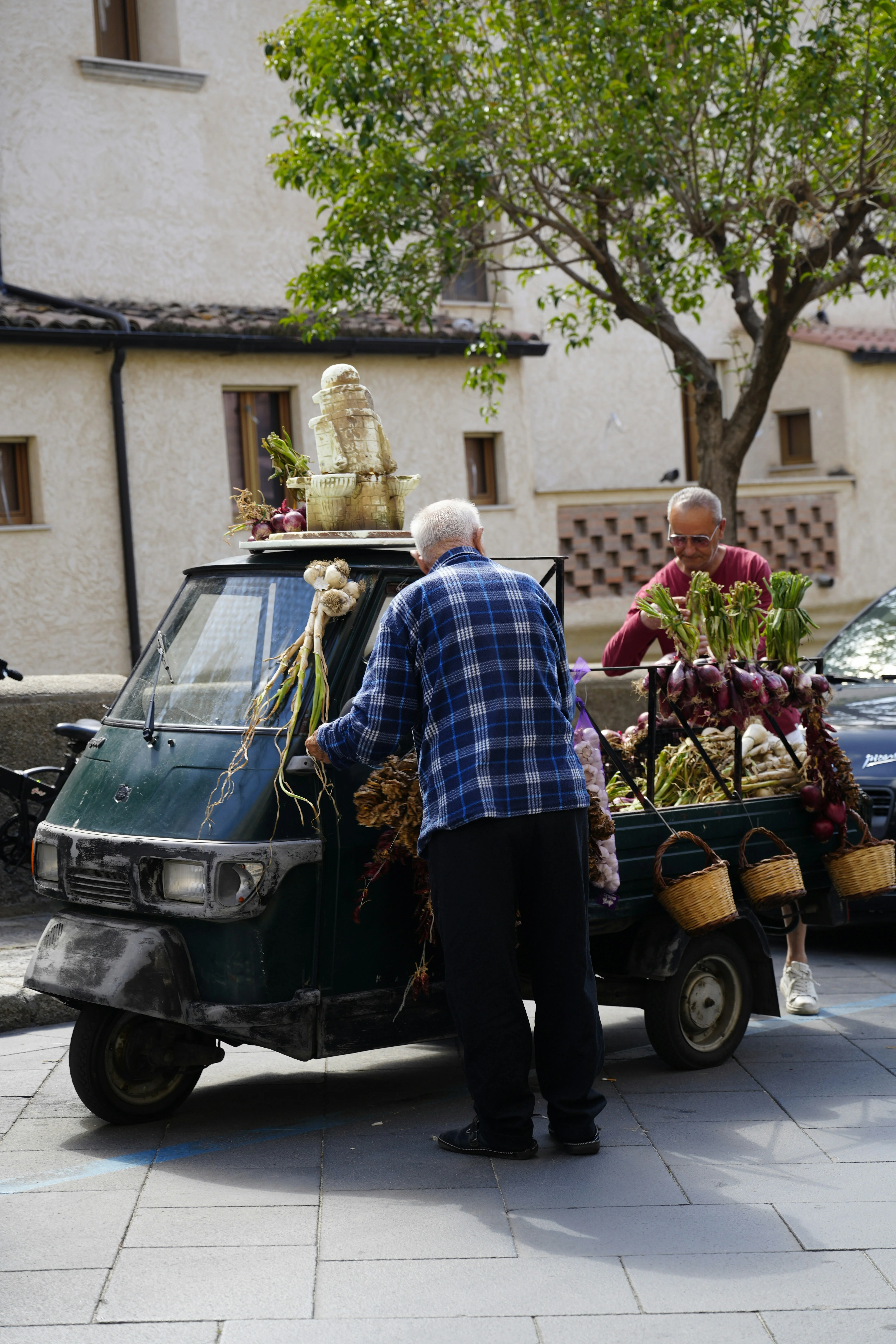 Local market scene with vendors selling fresh produce from a vintage three-wheeled vehicle