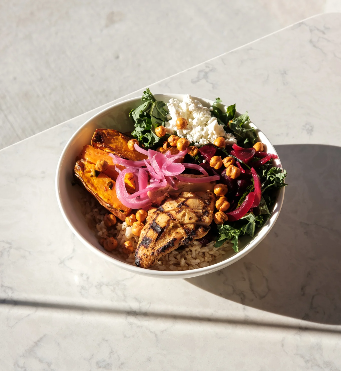 Grilled chicken grain bowl with kale and roasted vegetables