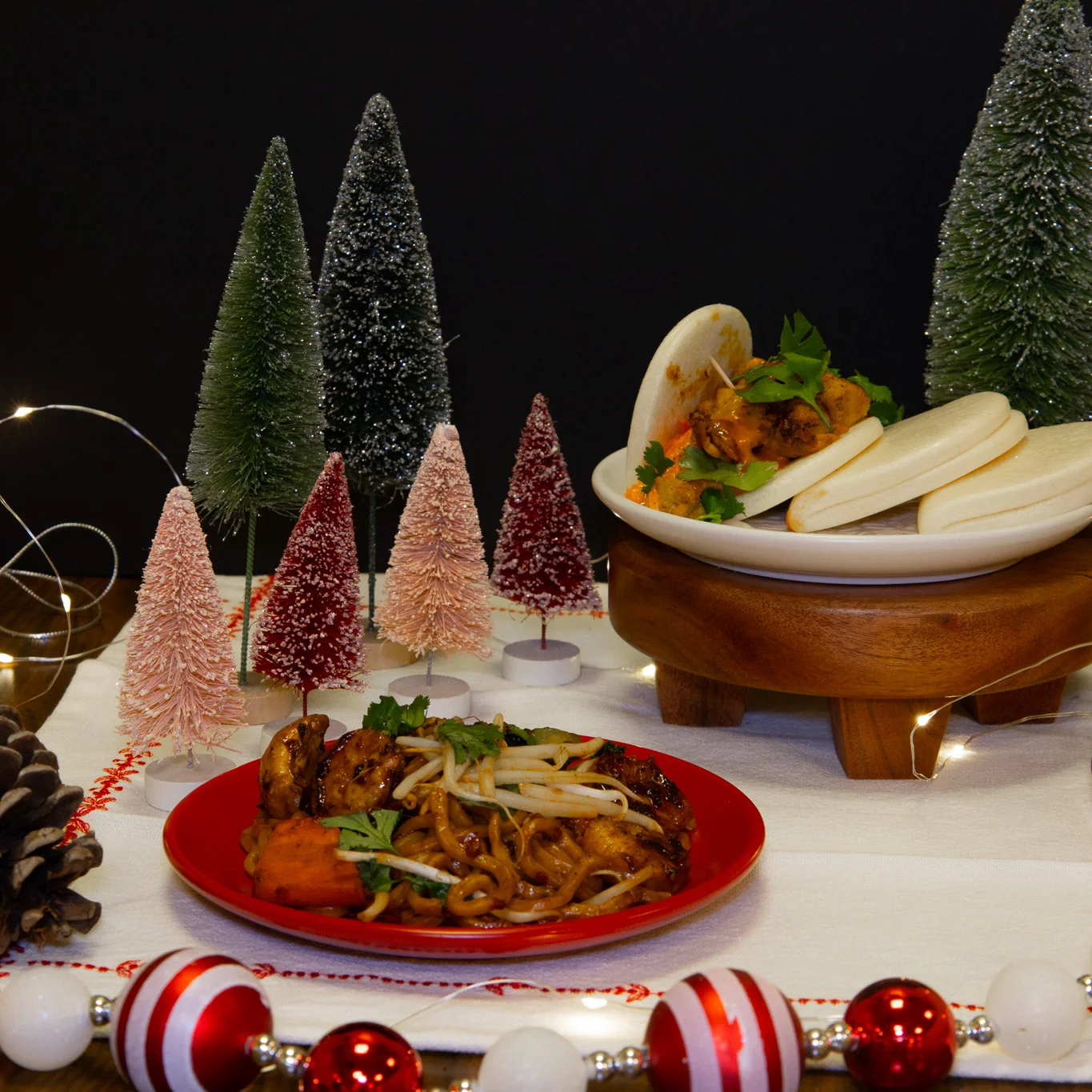 A plate of stir-fried noodles and a plate of love bao buns photographed in Christmas settings