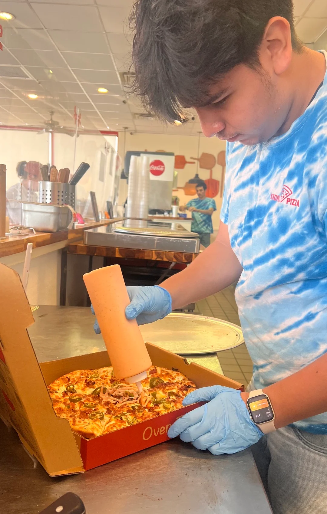Pizza being prepared with sauce in a pizzeria