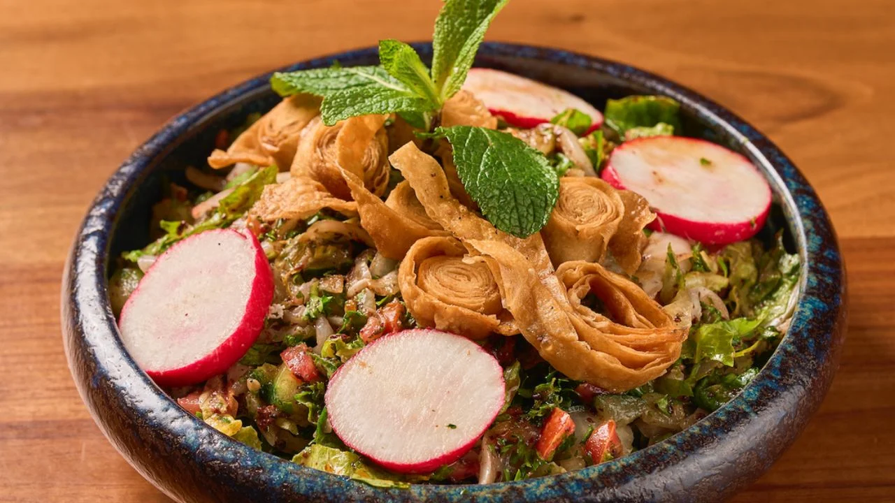 Fattoush salad with lettuce, cucumber, tomatoes, onion, parsley, sumac, topped with pita chips.
