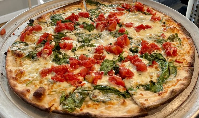 Fresh Margherita pizza topped with spinach and tomatoes