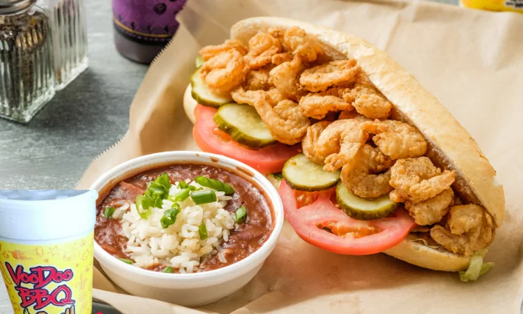 Shrimp Po’ Boy from VooDoo BBQ in Pensacola, made with crispy fried shrimp on Leidenheimer French bread with tomatoes, pickles, and a side of red beans and rice.