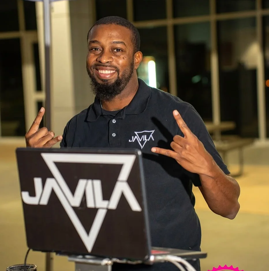 Smiling DJ at an event with a laptop and vibrant atmosphere