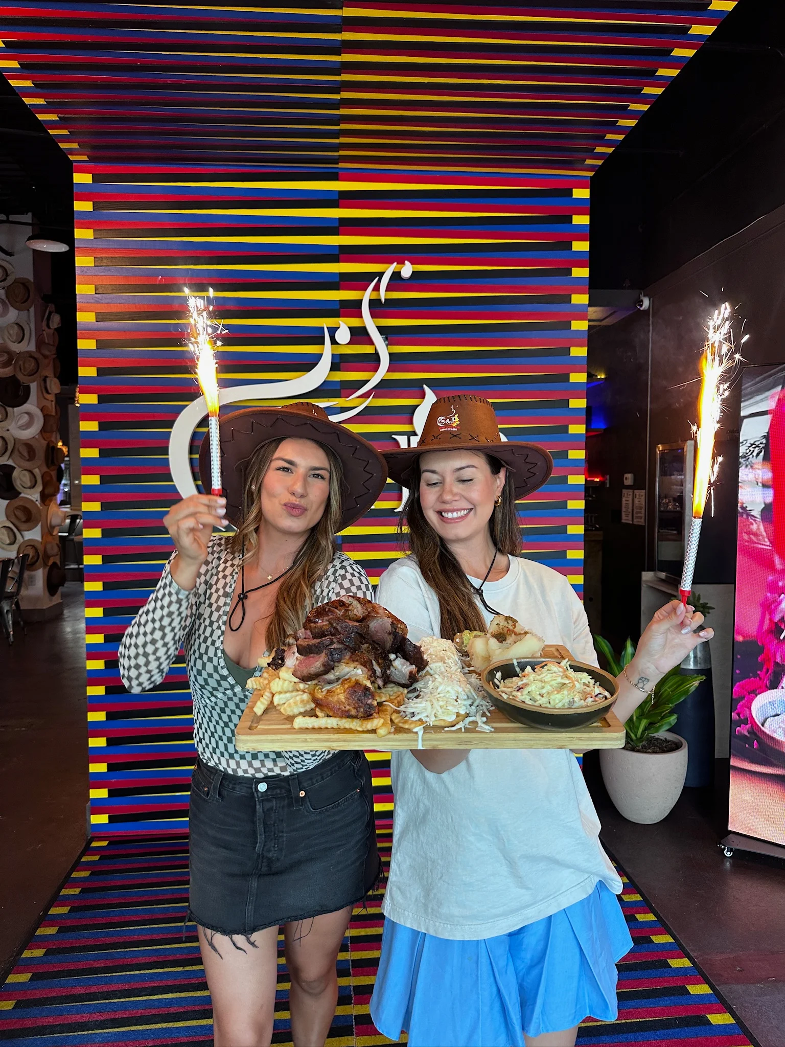 Two women celebrating with a platter of barbecue and sparklers