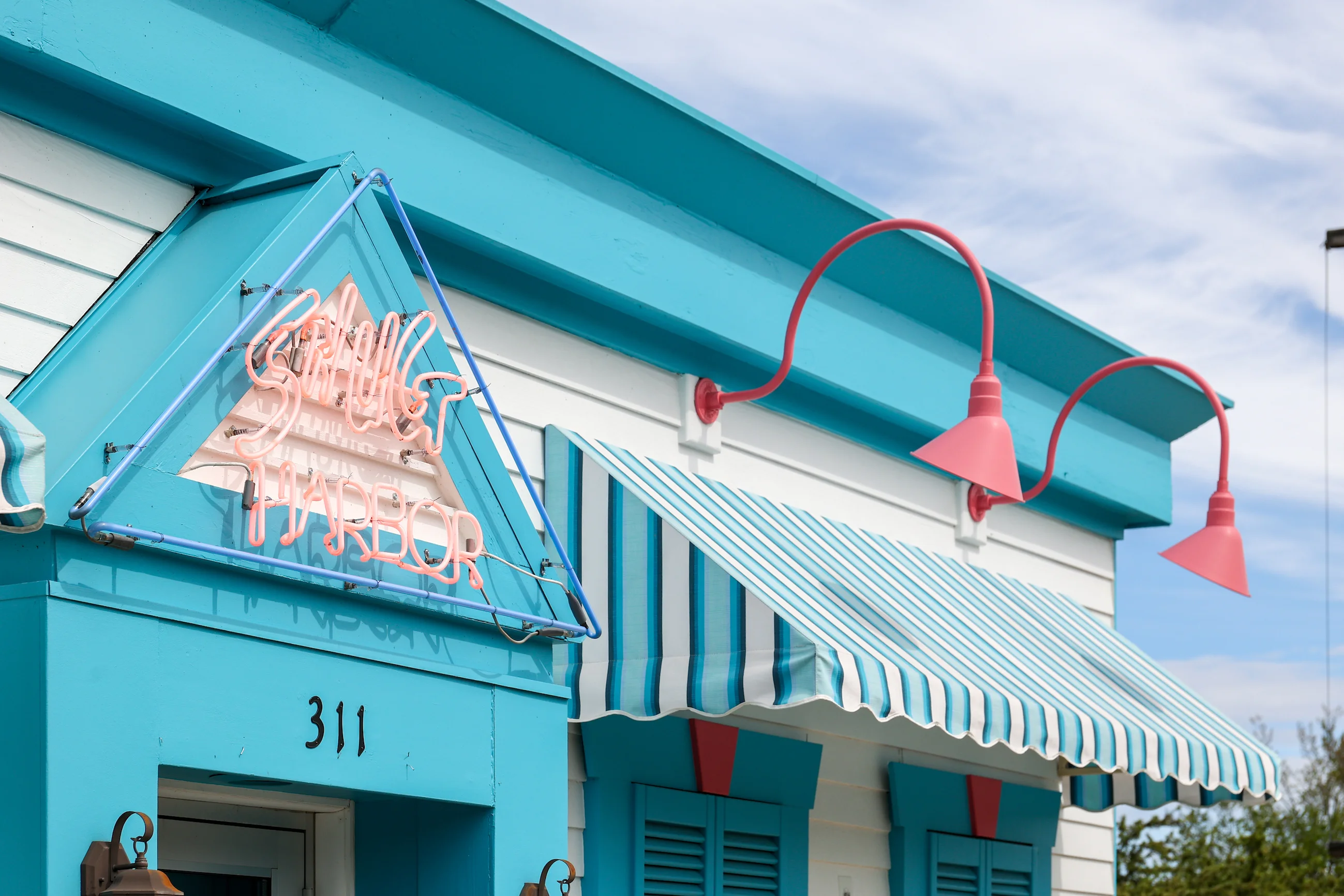 Colorful restaurant exterior with neon sign and striped awning