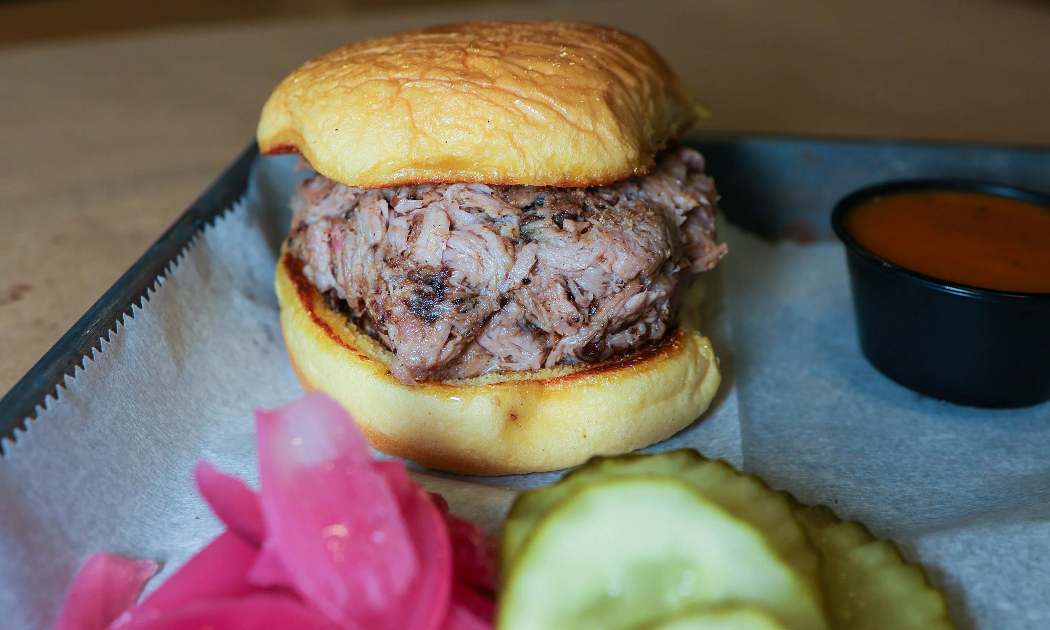 Pulled pork sandwich with pickles and sauce