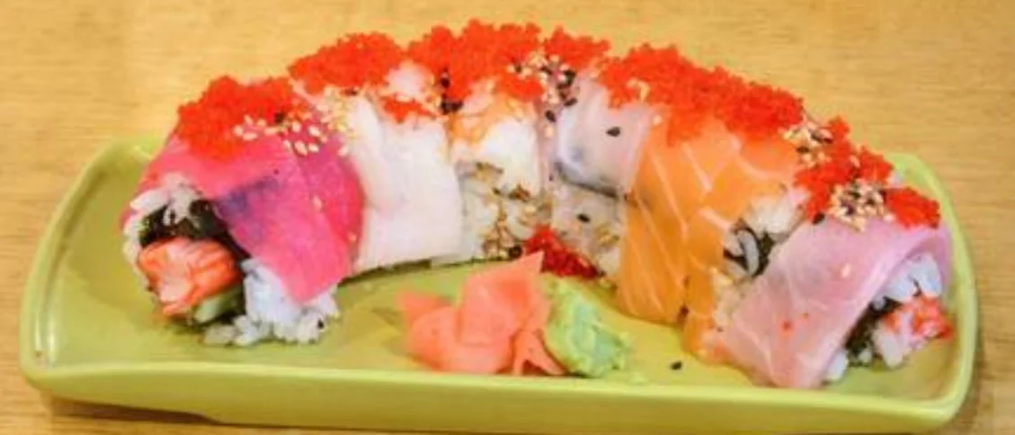 Rainbow sushi roll with fresh tuna, salmon, yellowtail, and avocado topped with flying fish roe, served with wasabi and pickled ginger at Sushi Kim 2