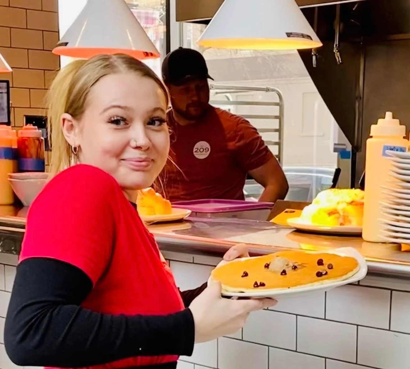 Server holding food with a happy smile.