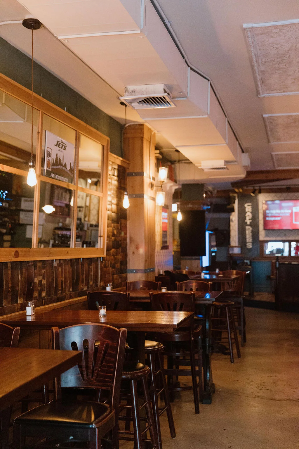An empty restaurant interior featuring wooden tables and chairs, with warm lighting and a rustic decor style.
