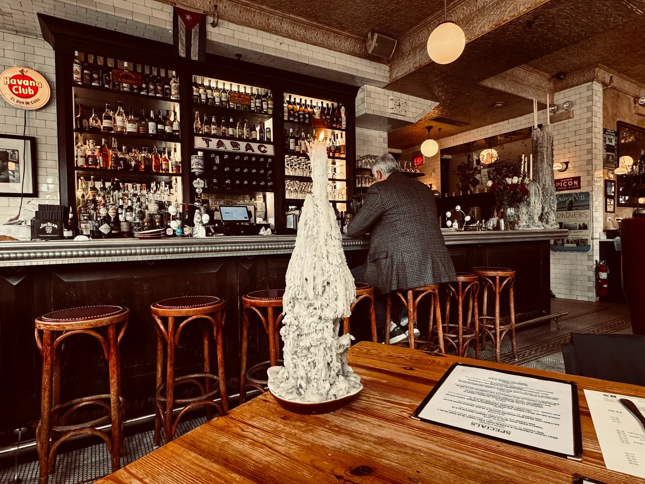 Cozy bar interior with wooden stools and a well-stocked liquor shelf