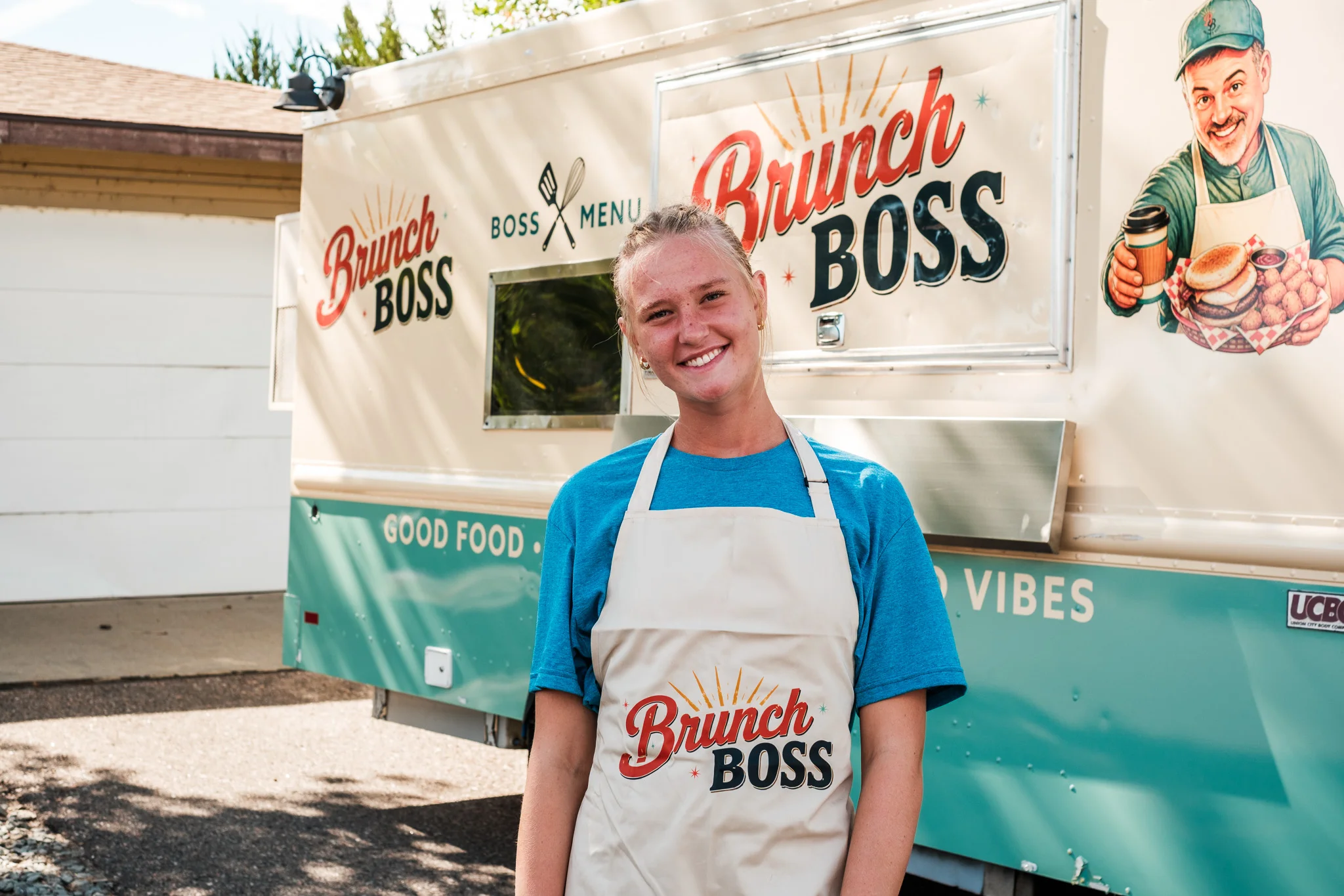 Smiling staff member in front of a food truck named Brunch Boss
