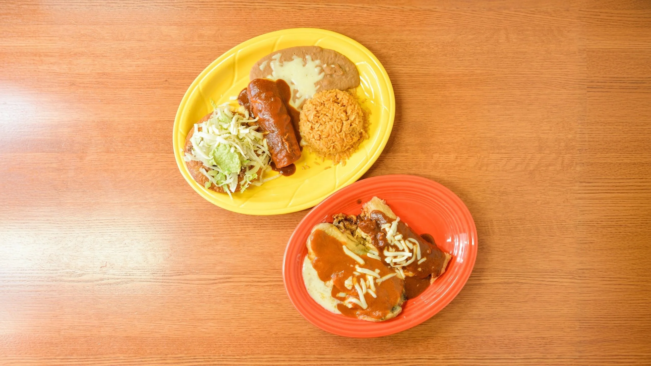 Authentic Mexican enchiladas with rice and beans on colorful plates