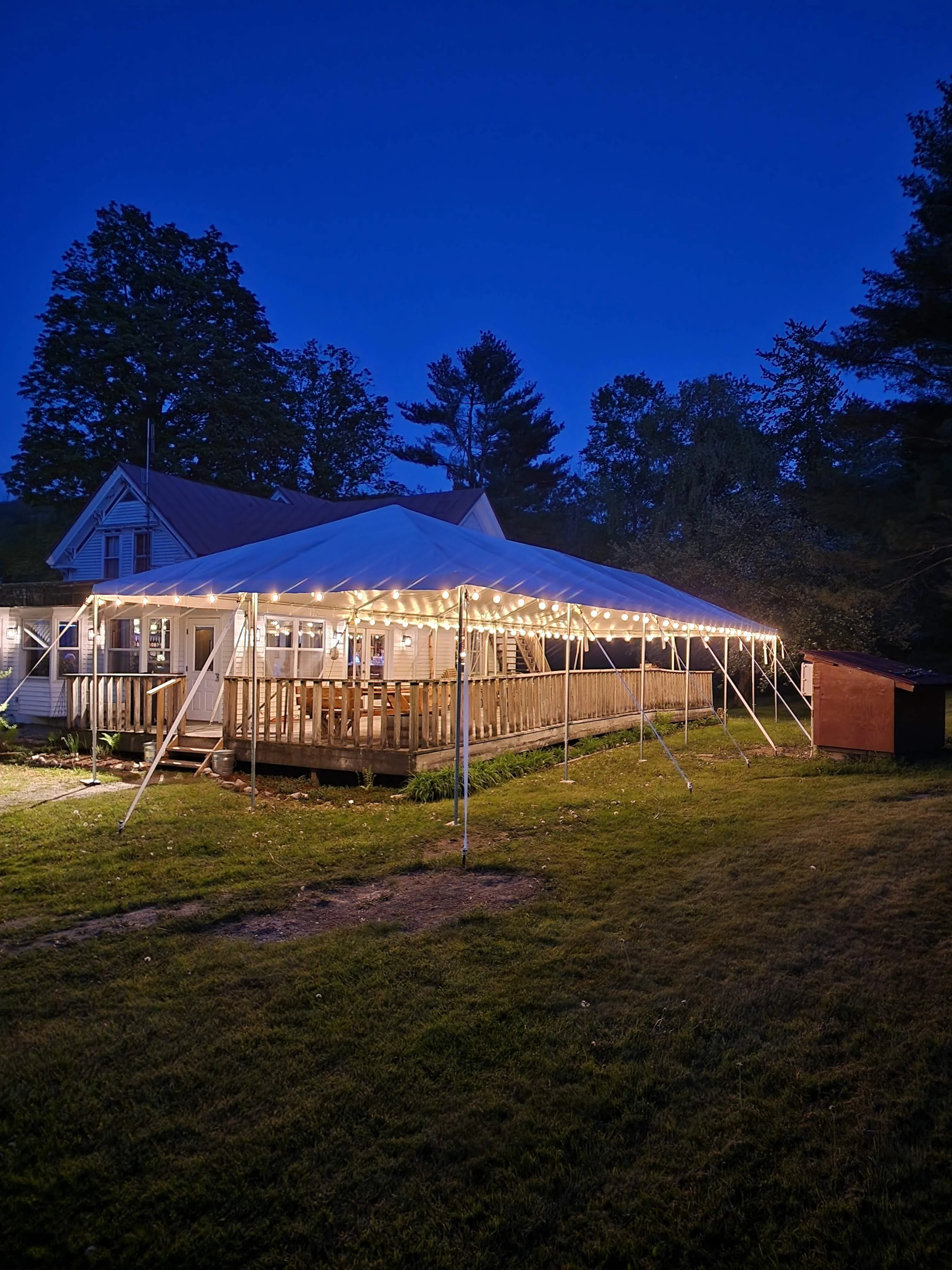Historic restaurant building with illuminated outdoor event tent at dusk