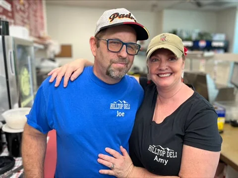 Friendly deli owners posing in their restaurant
