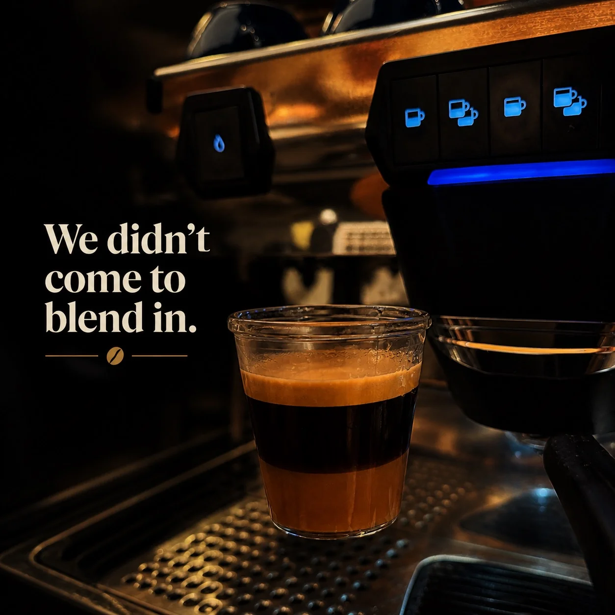 A layered coffee drink in a clear cup with an espresso machine in the background.