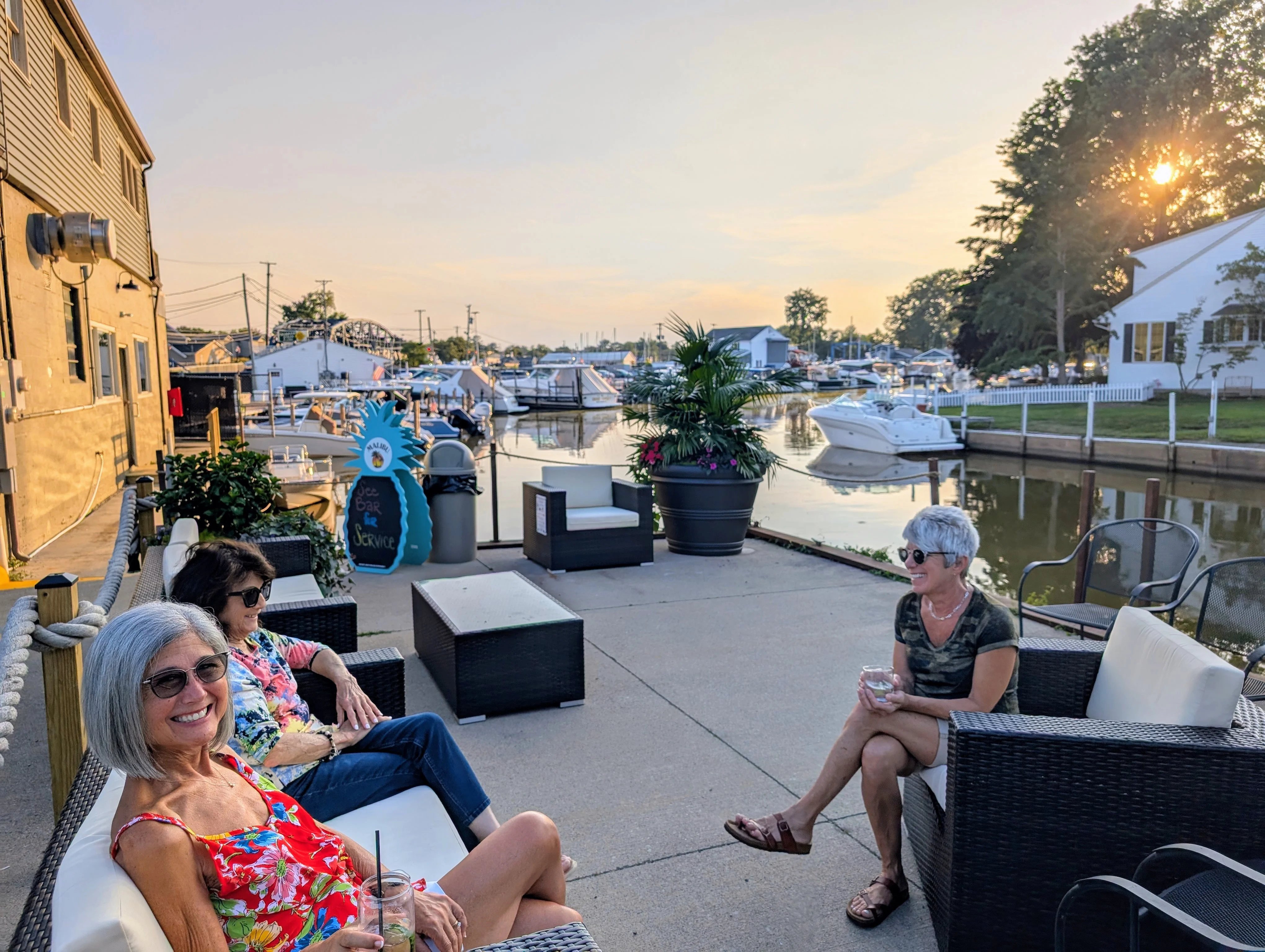 Outdoor seating by the marina at sunset with friends enjoying drinks