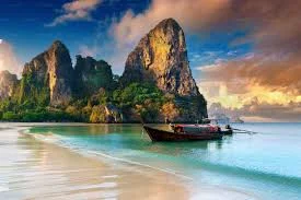 Scenic beach with a boat and rocky cliffs at sunset