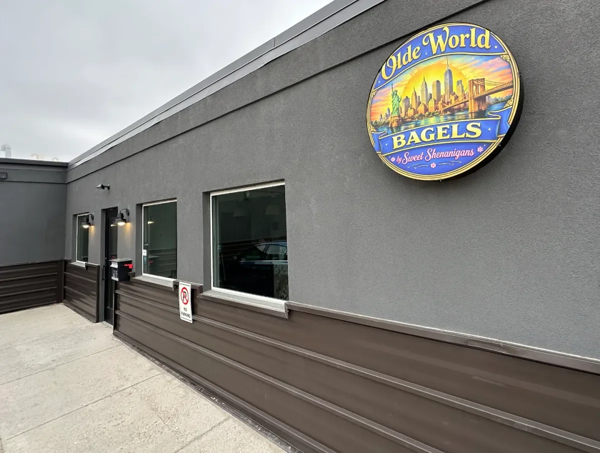 The exterior of a bagel shop with a prominent sign and large windows.