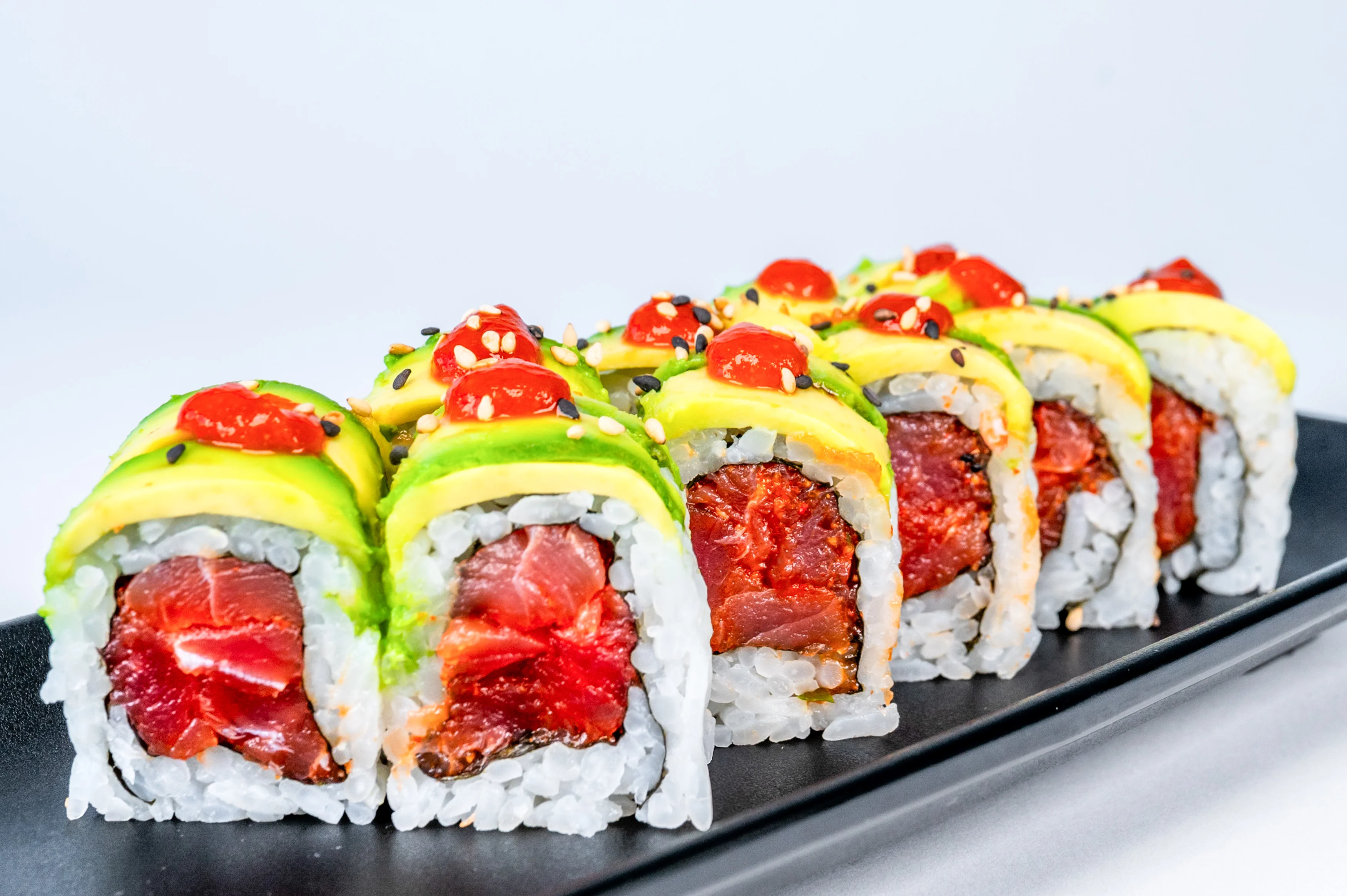 Colorful sushi rolls with avocado and spicy sauce