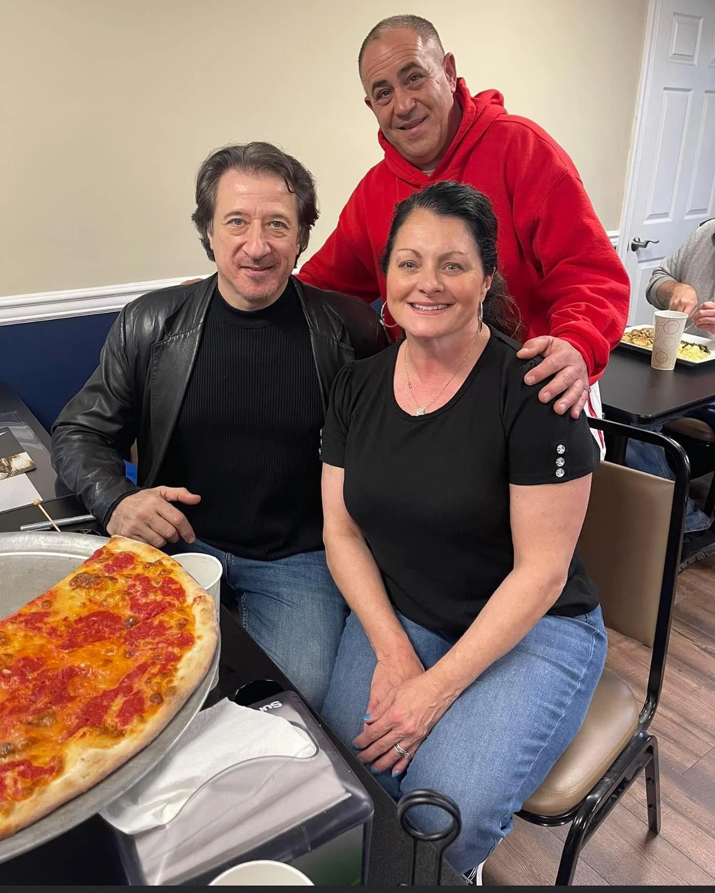 Group enjoying a large Margherita pizza in a cozy restaurant setting
