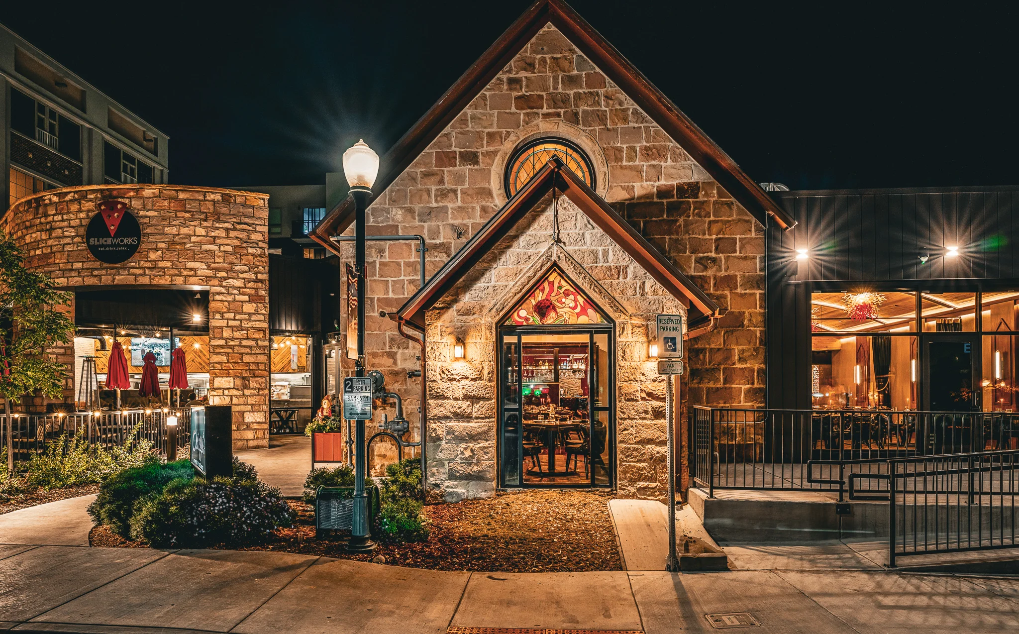 Nighttime exterior of a stone restaurant with glowing stained glass entrance